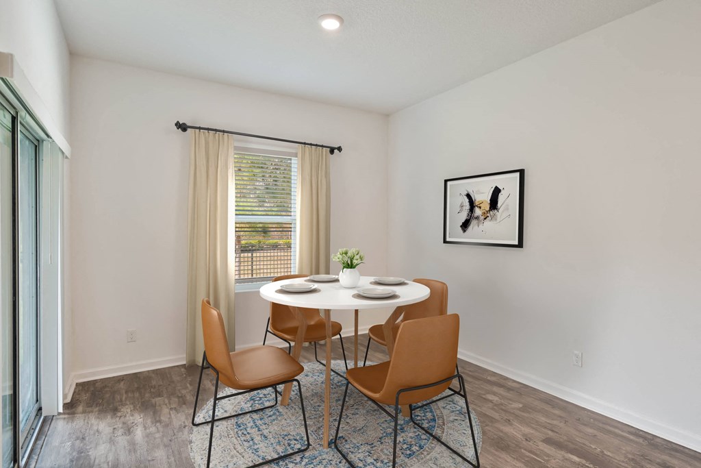 A dining room with a table set for two and a framed picture of a bird on the wall.