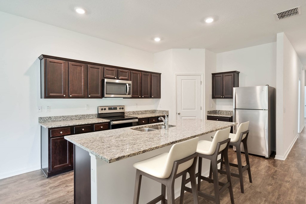 A kitchen with brown cabinets and a granite countertop.