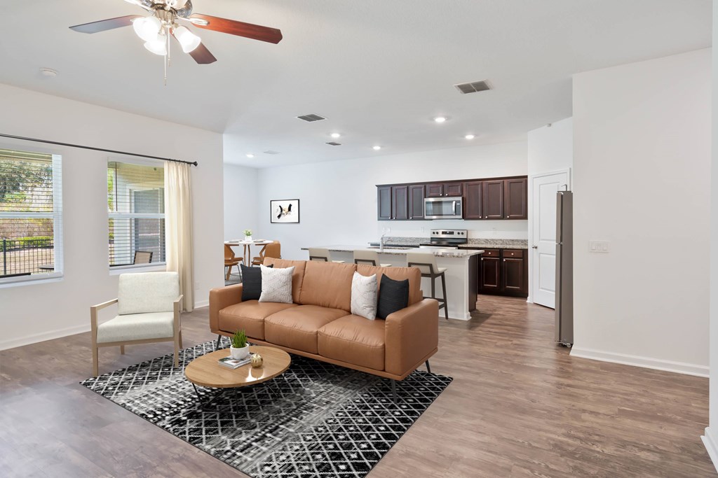 A living room with a brown couch and a ceiling fan.