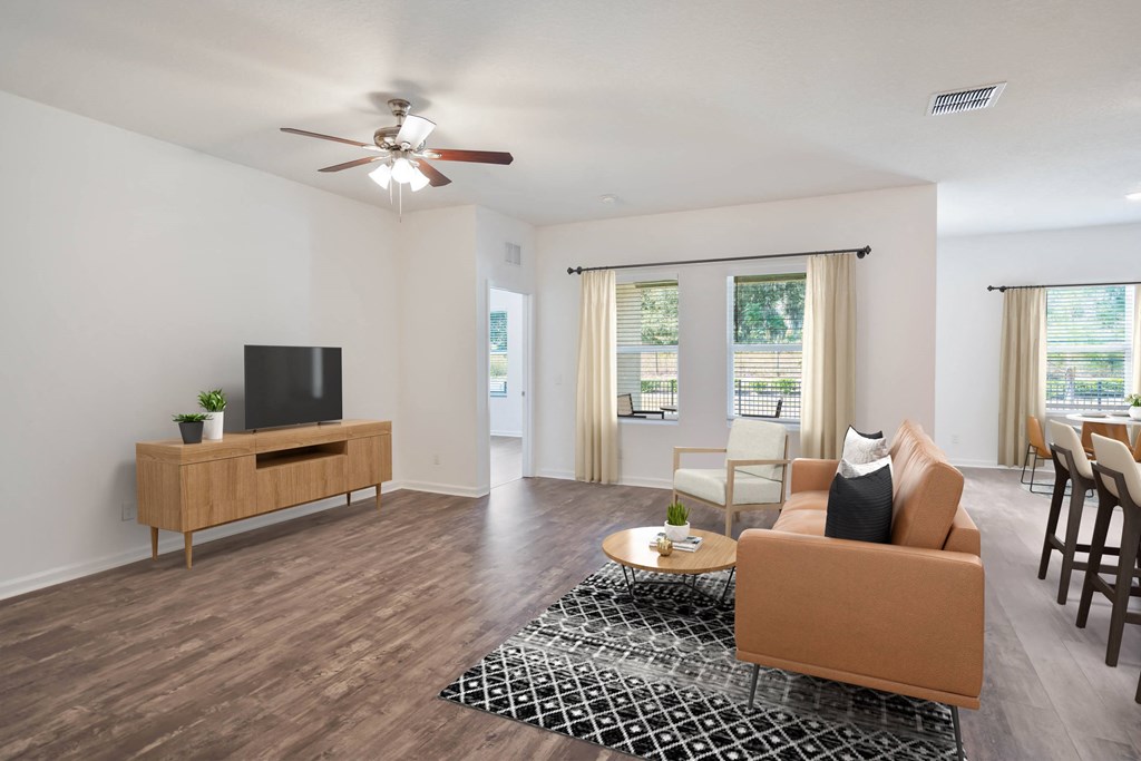 A living room with a brown sofa, a wooden entertainment center, and a ceiling fan.