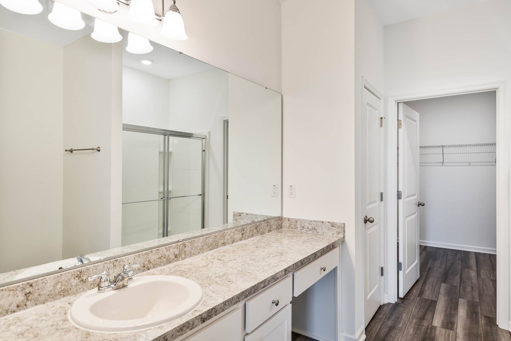 A bathroom with a sink, mirror, and wooden floors.