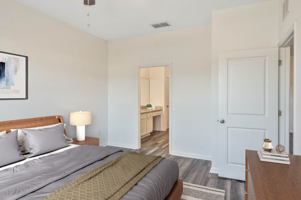 A bedroom with a bed, nightstand, and a painting on the wall.