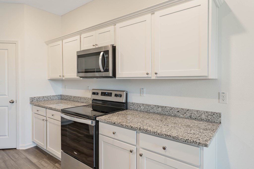 A kitchen with granite countertops and white cabinets.