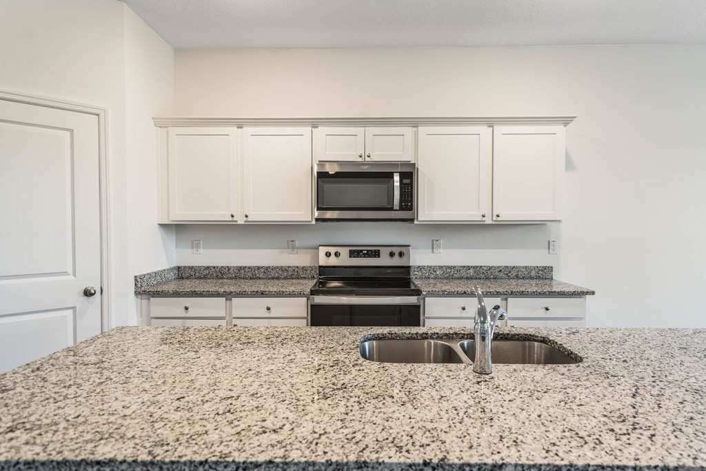 A kitchen with granite countertops and white cabinets.
