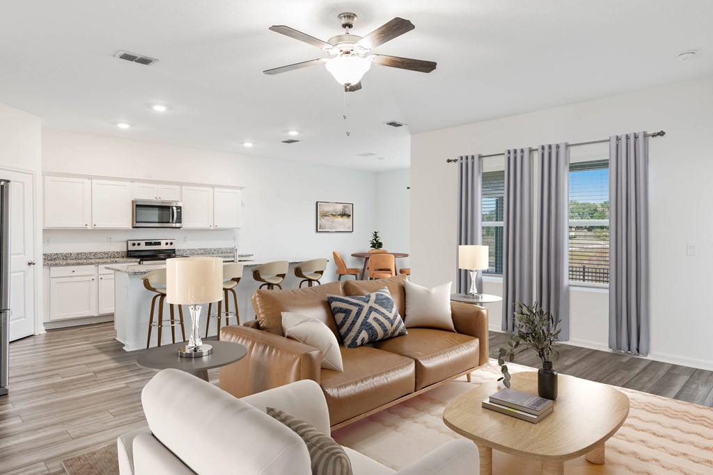 A modern living room with a brown leather couch and a white kitchen in the background.