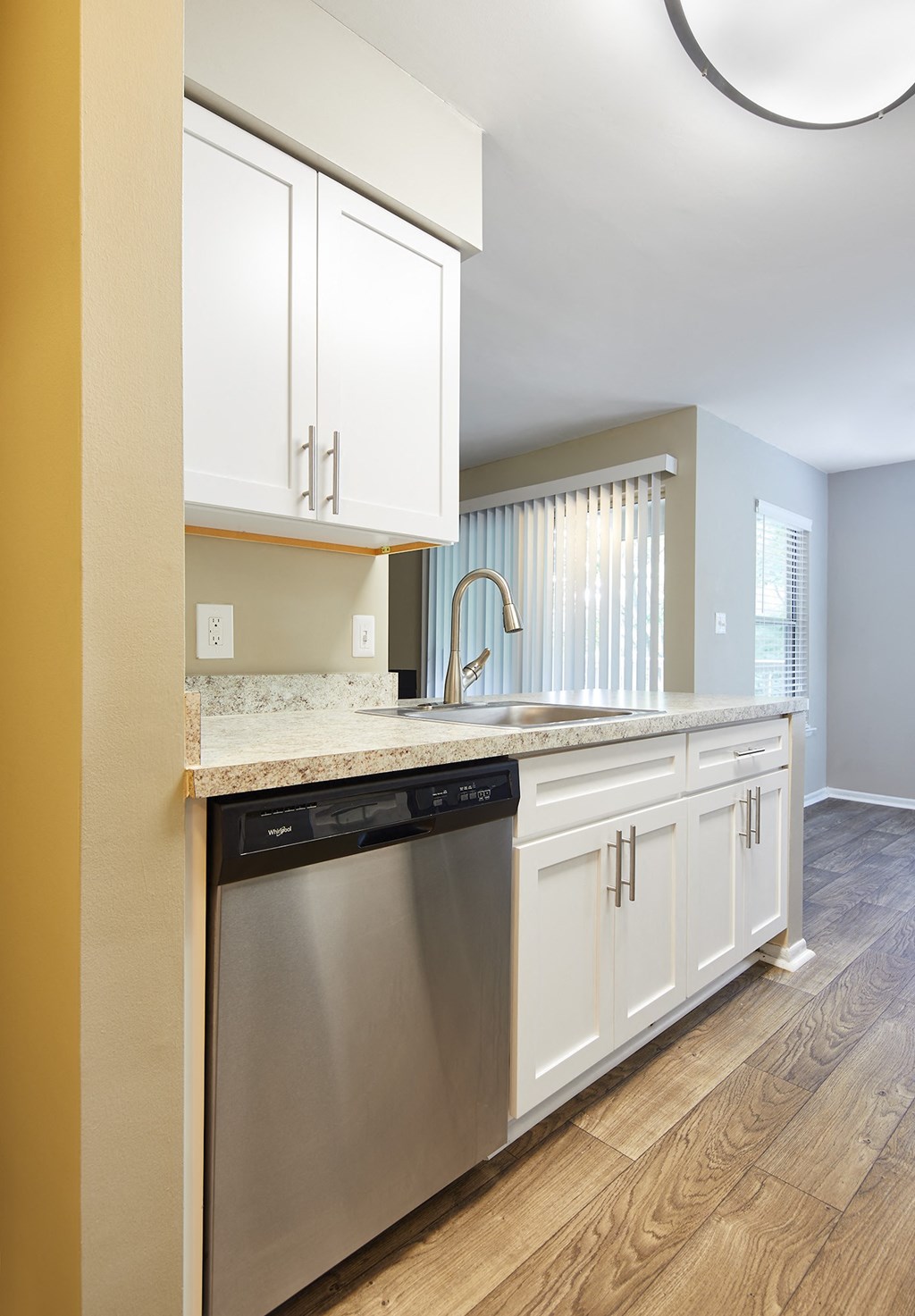 a kitchen with white cabinets and a stainless steel dishwasher