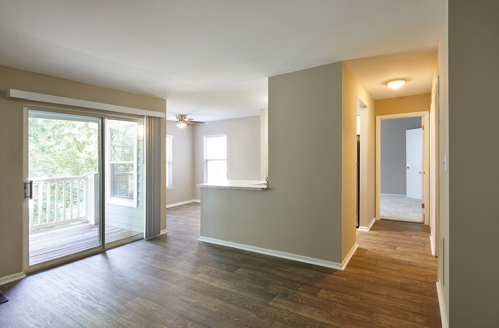 an empty living room with a sliding glass door to a balcony