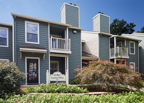 an apartment building with blue siding and a white sign
