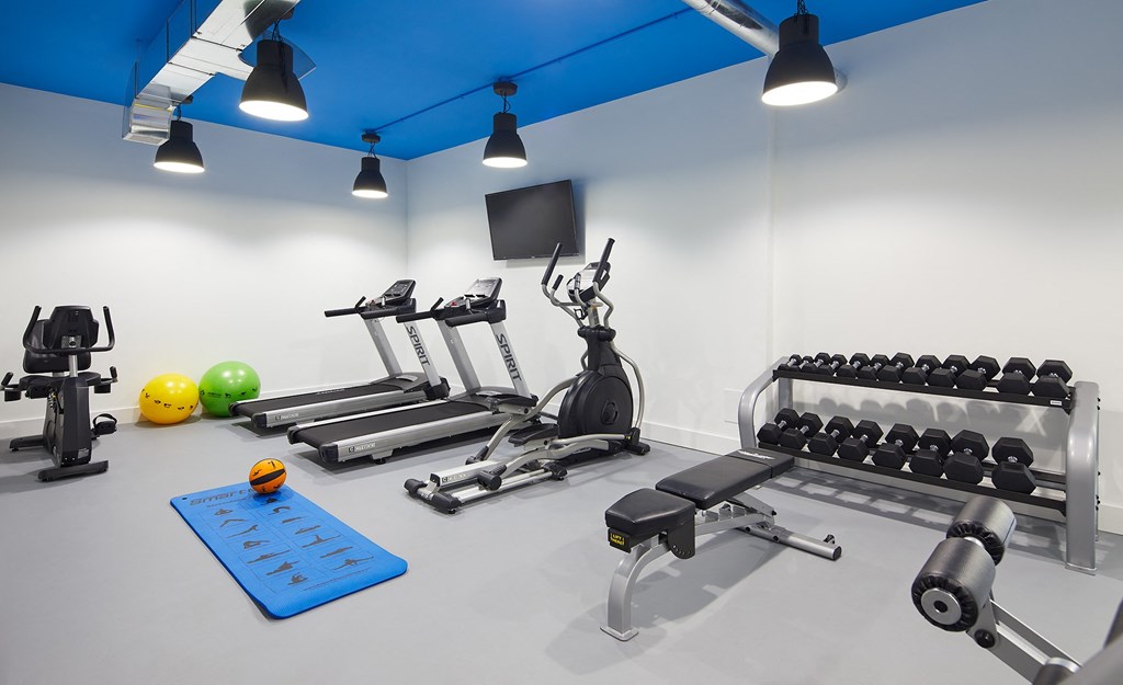 a workout room with weights and a tv in the corner of a building