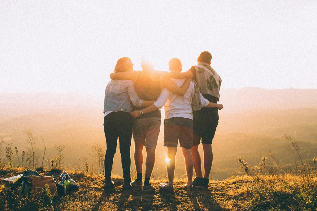 a group of people standing on a hill with their arms around each other