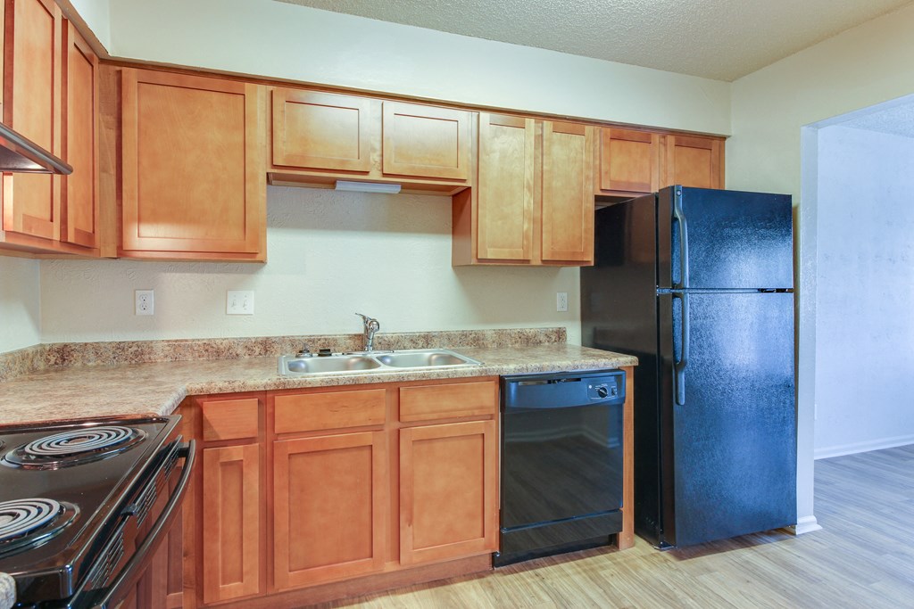 a kitchen with wooden cabinets and a black refrigerator