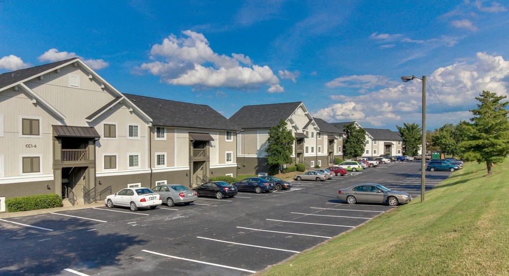 a parking lot with cars parked in front of apartment buildings