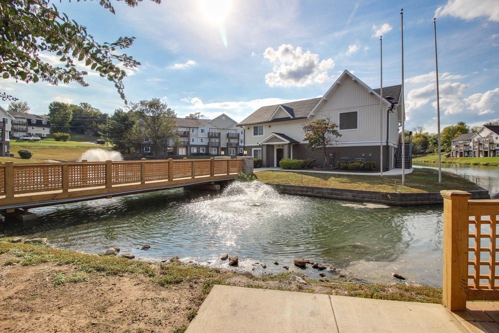 a bridge over a pond with houses in the background