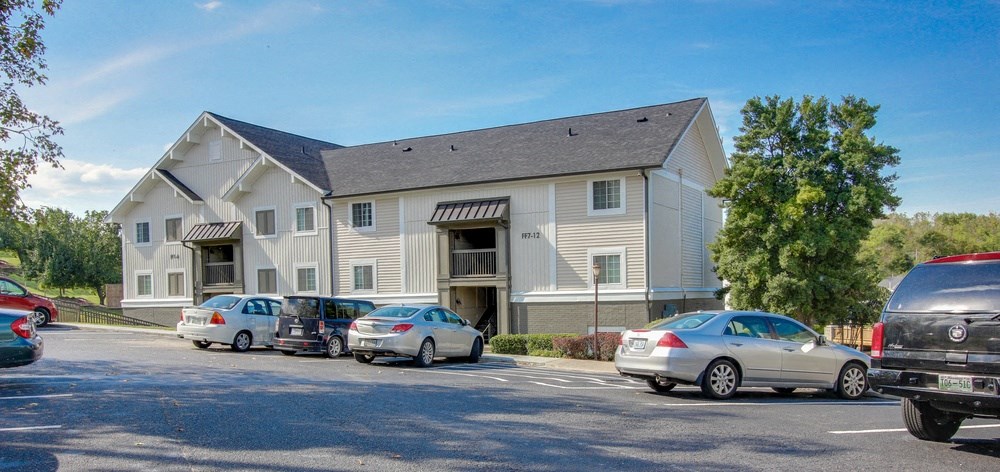 a parking lot with cars in front of an apartment building