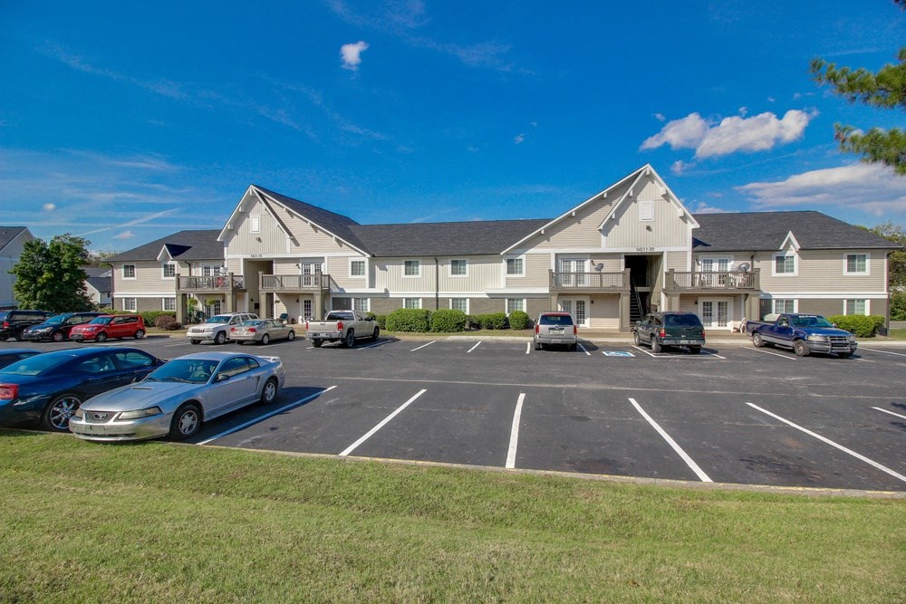a parking lot with cars in front of an apartment building