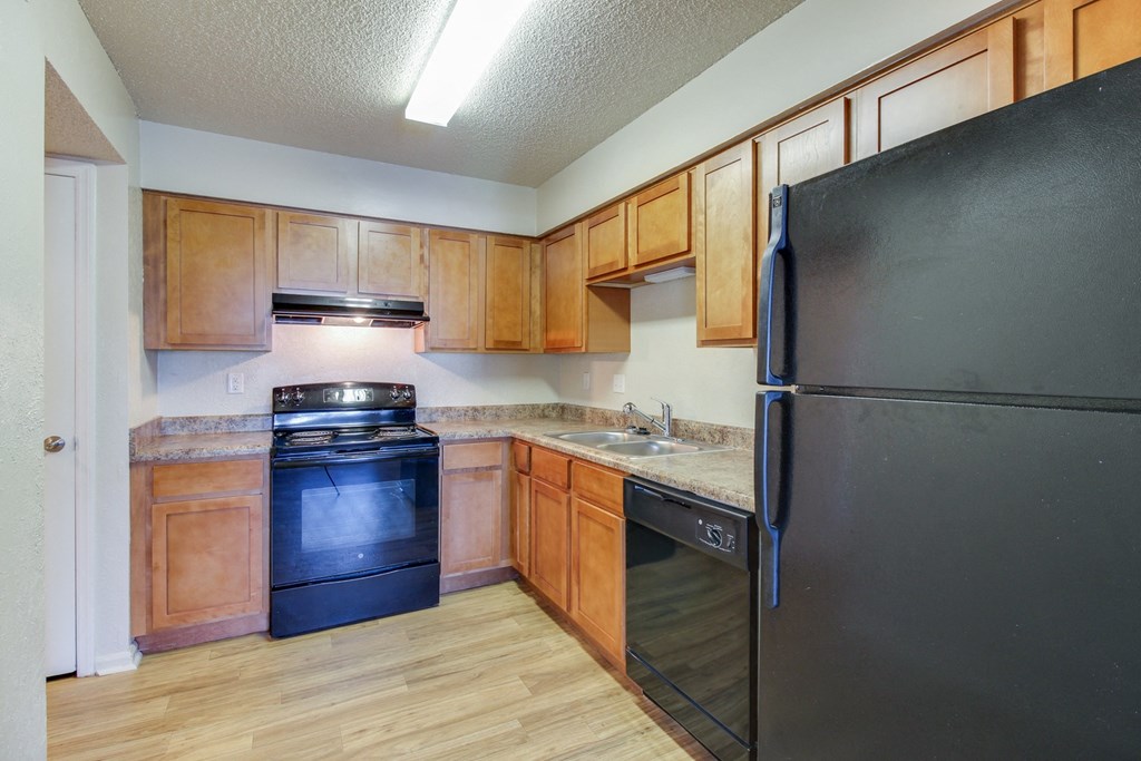 a kitchen with wooden cabinets and a black refrigerator