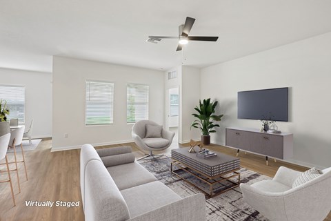 A living room with a grey couch, a chair, a coffee table, and a television.