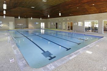 a large indoor swimming pool with a wood ceiling and stone flooring