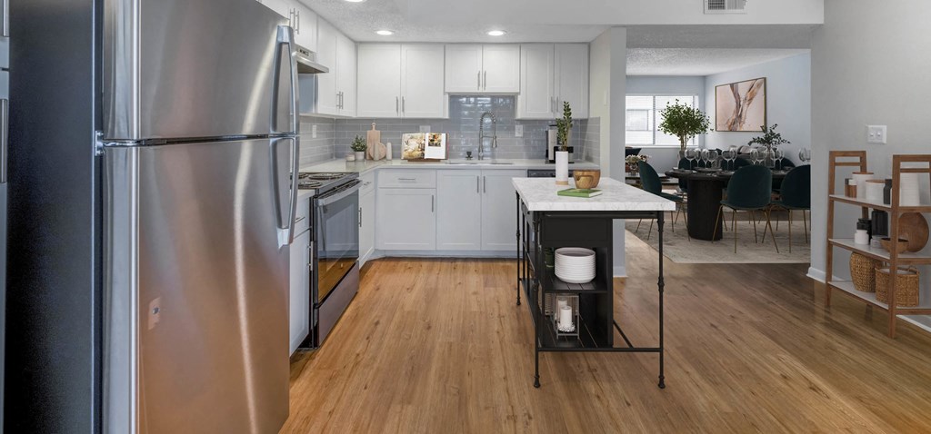Modern kitchen with stainless steel appliances, white cabinets, island, and dining area.