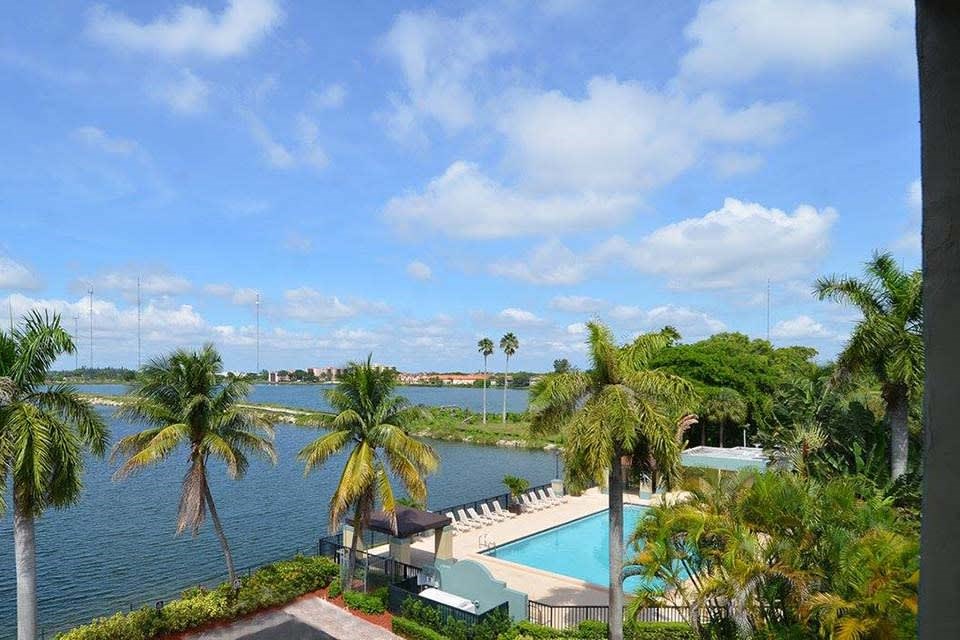 Tropical resort view overlooking a lake and swimming pool with palm trees.