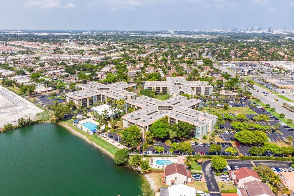 Aerial view of a residential apartment complex with swimming pools and lakefront property.