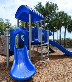 Blue playground slide and climbing structure on wood chip surface.