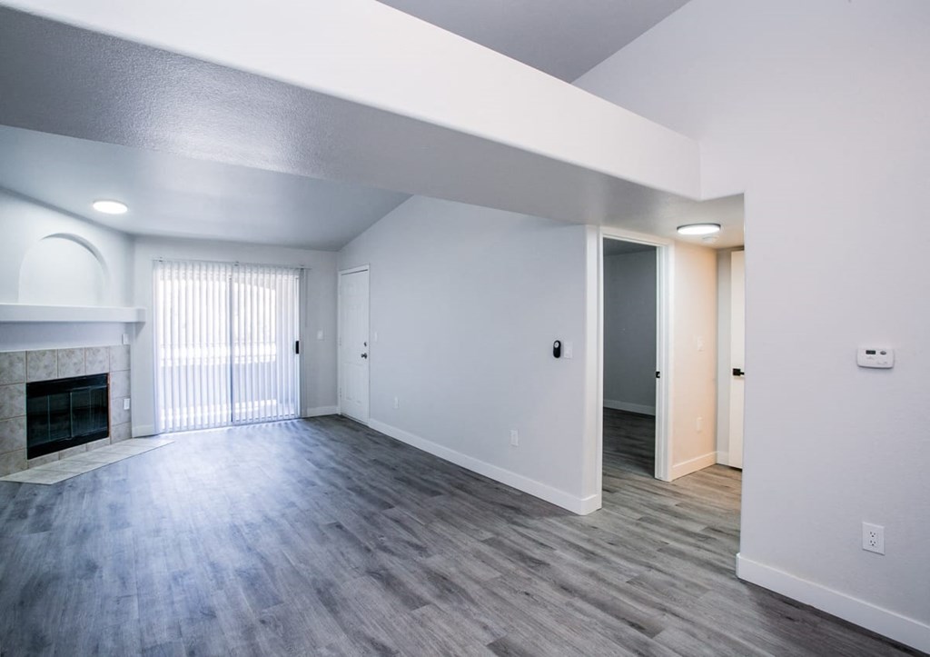an empty living room with a fireplace and hardwood floors