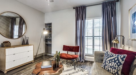 A living room with a red chair and a grey couch.