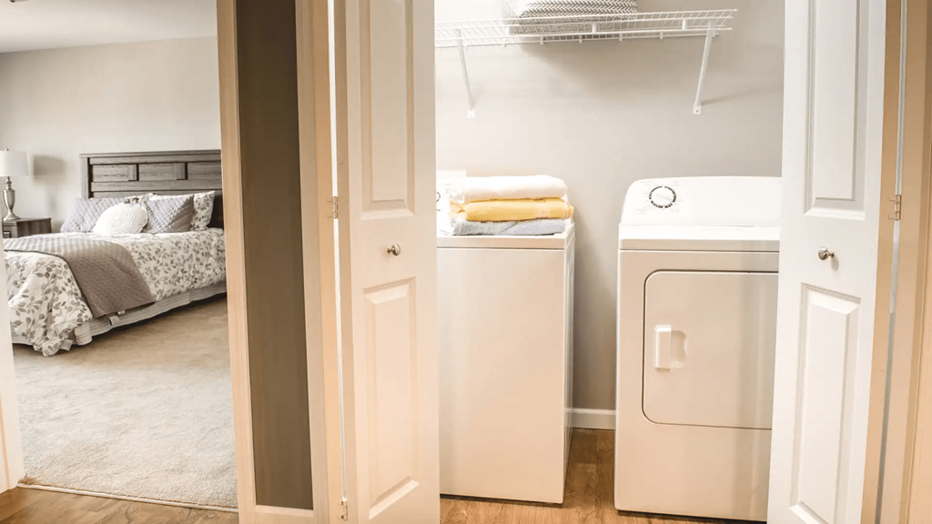 a bedroom with a washer and dryer and a closet with a bed