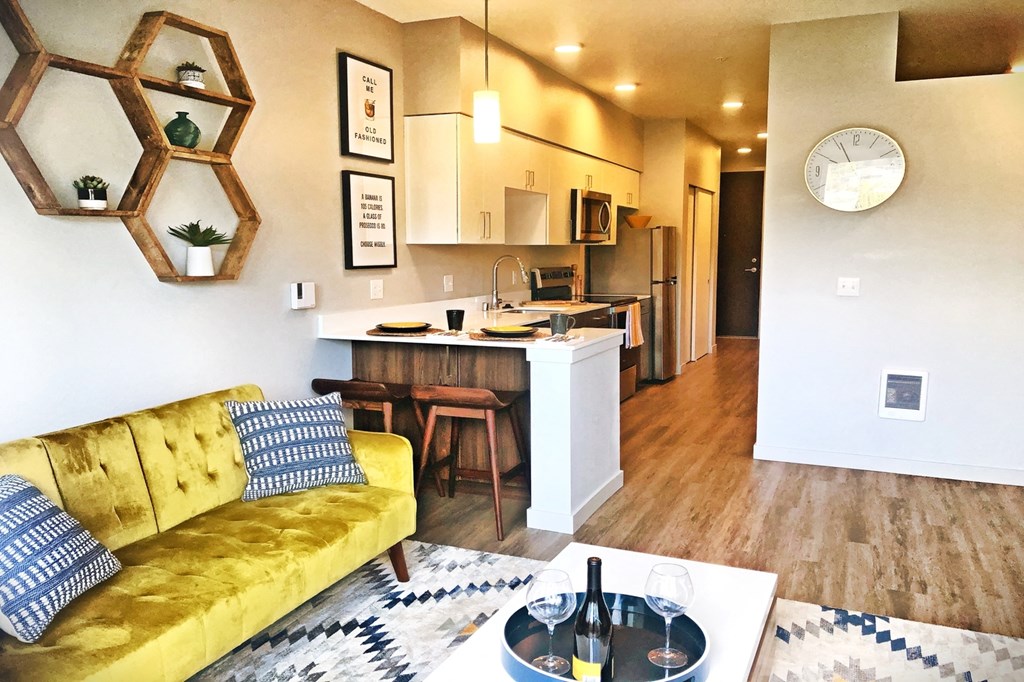 Apartments in Bothell for Rent - 98th Avenue - An interior shot of the spacious living room featuring wood flooring, access to the kitchen, and modern finishings