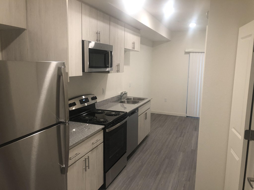 Apartments For Rent in Downtown Phoenix, AZ - VB on 12th Street - Kitchen with Wood-style Flooring, White Cabinetry, Stainless Steel Appliances, and Grey-Granite Countertops