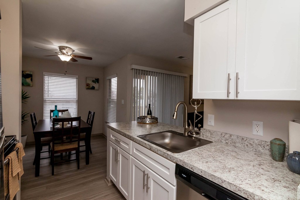 a kitchen with a sink and a dining room with a table