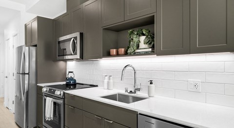 A modern kitchen with dark brown cabinets and stainless steel appliances.
