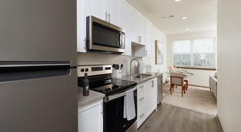 A modern kitchen with white cabinets and stainless steel appliances.