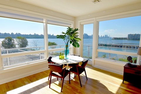 A dining room with a table and chairs and a view of the water.
