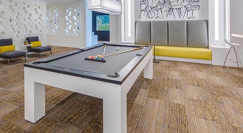 A pool table in a room with a bench and a drawing on the wall.
