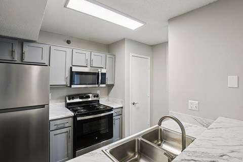 A kitchen with a stainless steel refrigerator, microwave, oven, and sink.