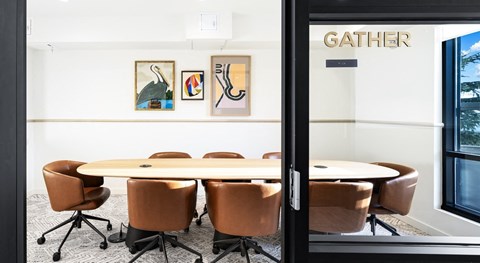 A conference room with a table and chairs and a sign that says GATHER.