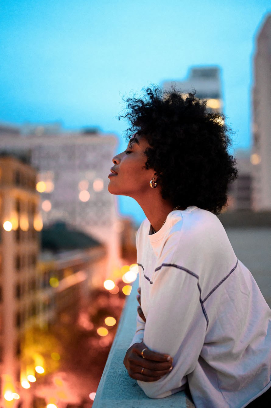 a woman standing on a balcony with the city in the background