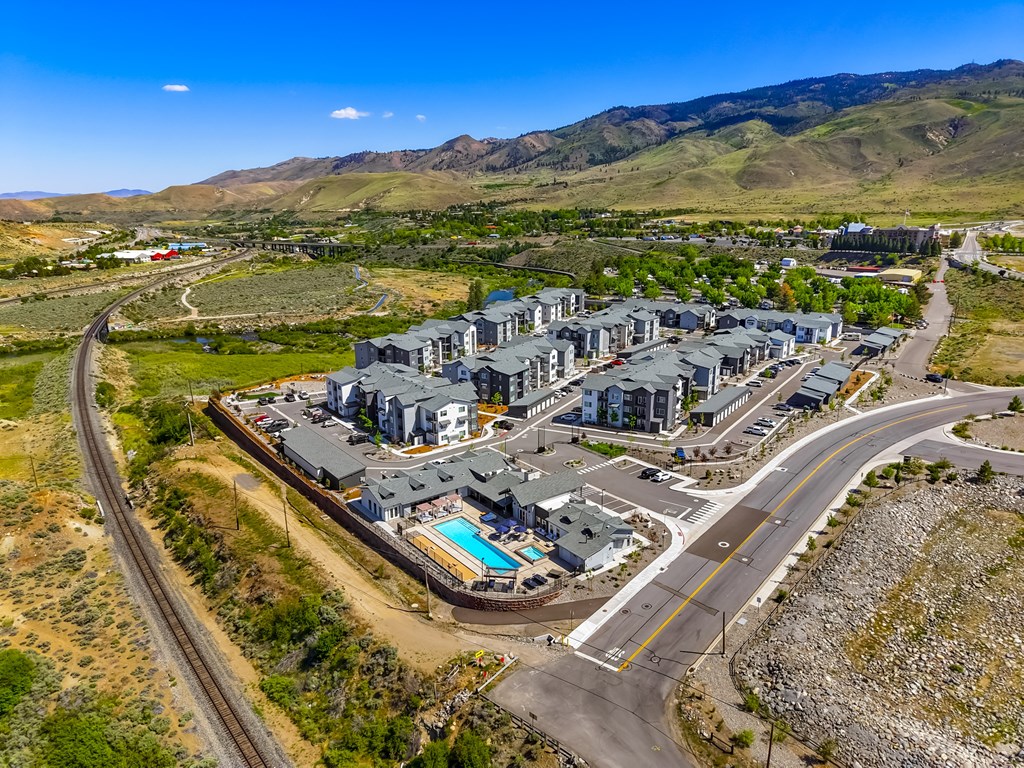 A large building complex with a swimming pool in the foreground and a winding road in the background.