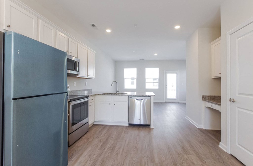 an empty kitchen with white cabinets and stainless steel appliances