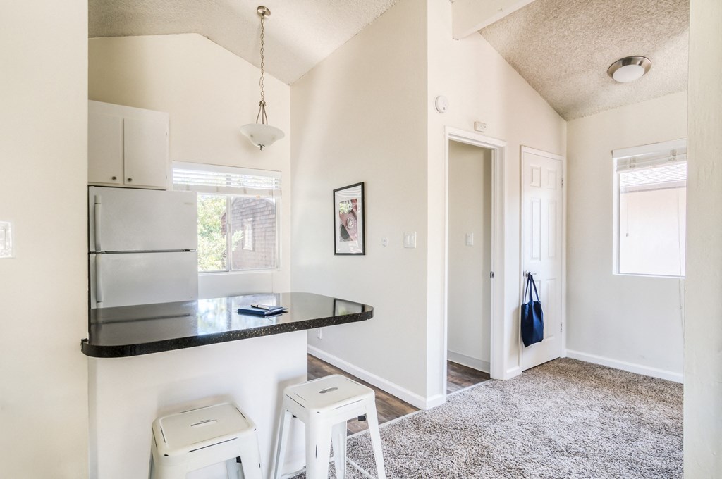 a kitchen with a black counter top and white stools