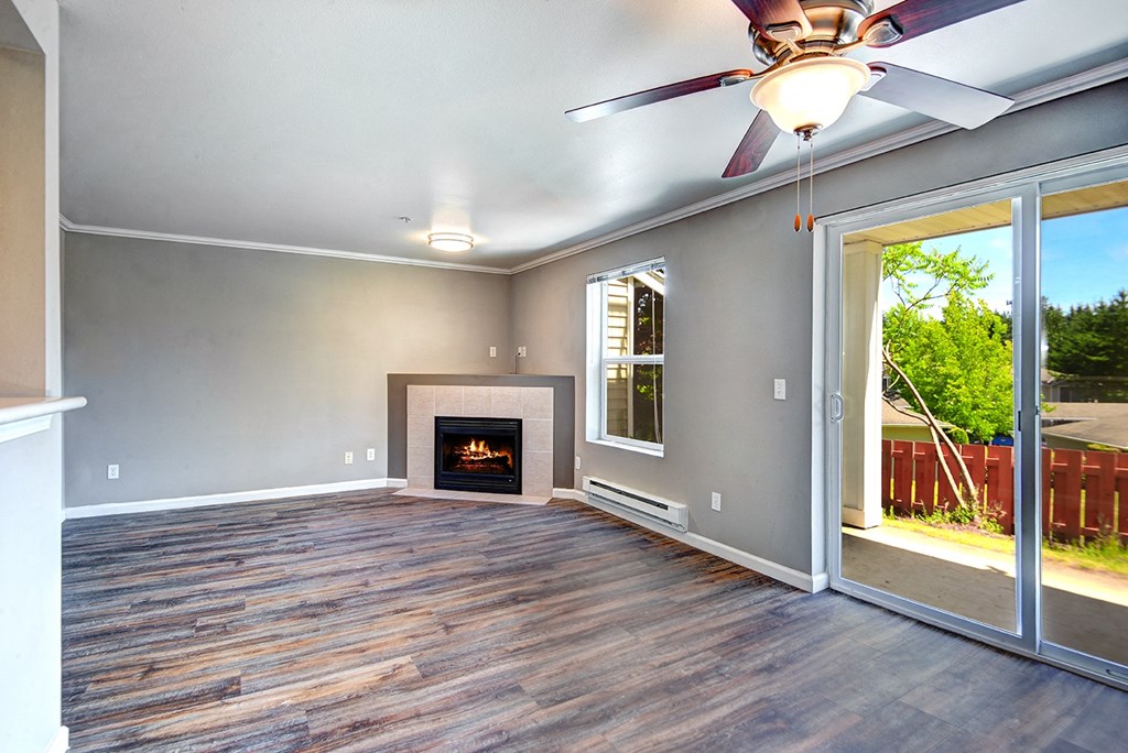 Apartments for Rent in Issaquah, WA - Langara - Living Room with Wood-Style Flooring, Window, Ceiling Fan, Fireplace, and Sliding Glass Door with Access to Patio