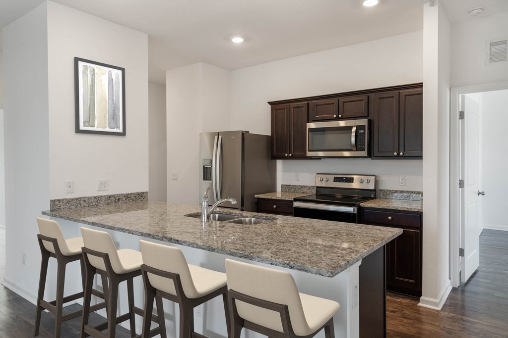 A kitchen with a granite countertop and bar stools.