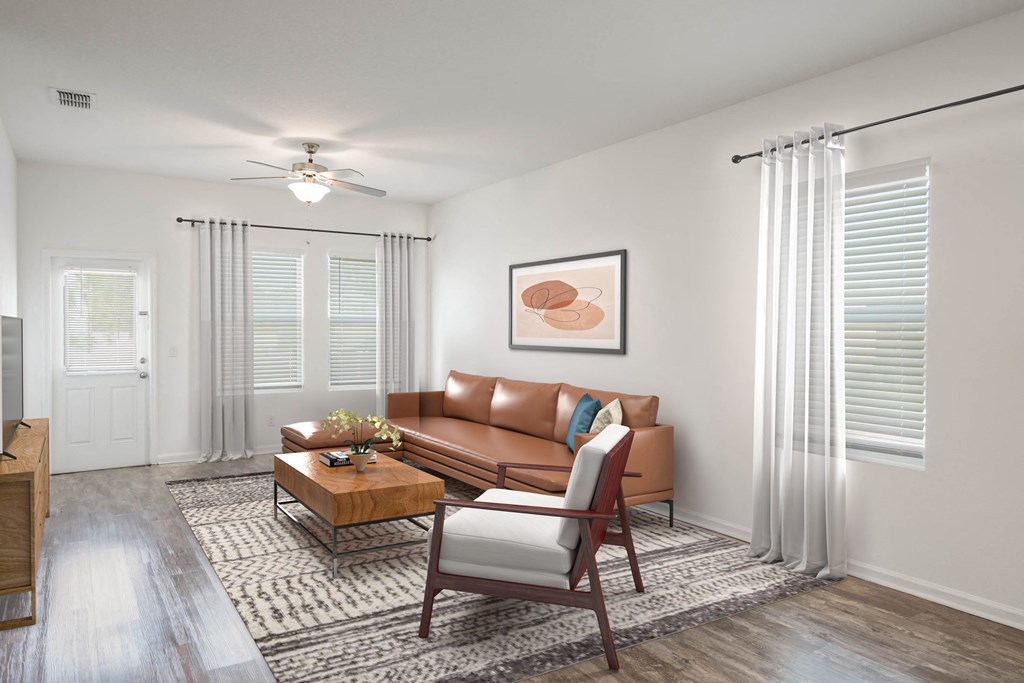 A living room with a brown couch, a coffee table, and a ceiling fan.