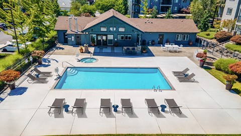 A pool with lounge chairs and a building in the background.