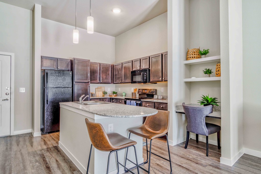 a kitchen with a bar and chairs and a refrigerator at LIV at Boerne Hills an Active Senior Community 62+, Boerne