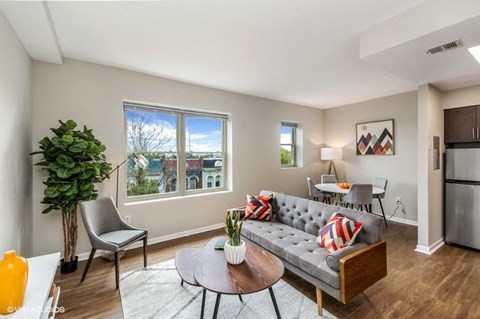 A living room with a grey couch, a chair, a table, and a potted plant.
