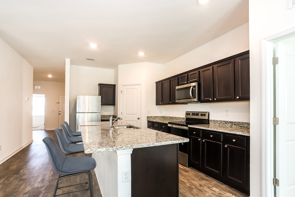 A kitchen with black cabinets and a granite countertop.