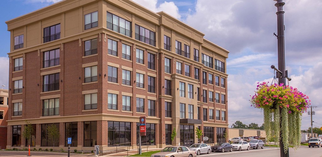 a large brick building with many windows and cars parked in front of it